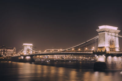 Illuminated bridge over river at night