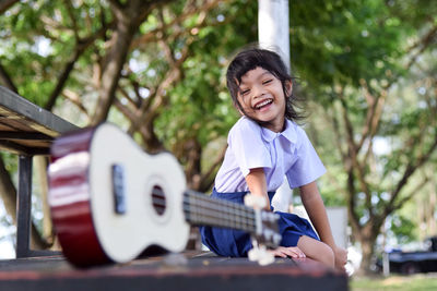 Close-up of guitar with cute girl sitting in background