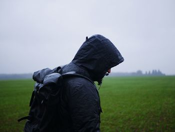 Side view of man standing on field against sky