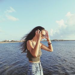 Young woman standing in sea against sky