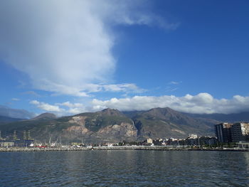 City at waterfront against cloudy sky