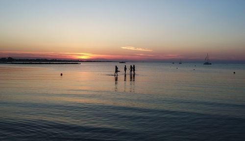 Silhouette people on beach against sky during sunset
