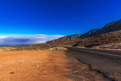 Road amidst desert against blue sky