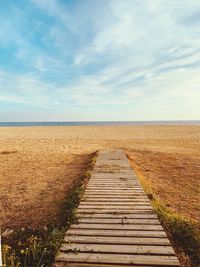 Boardwalk leading towards beach against sky