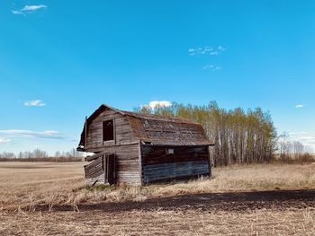 Old barn on field against blue sky