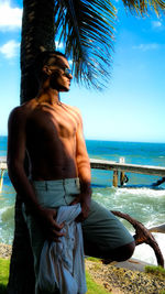 Full length of shirtless man standing on beach