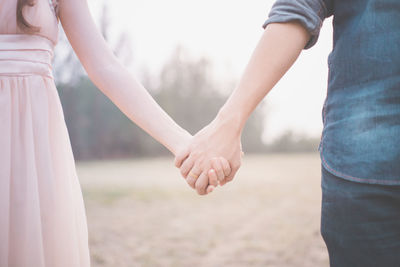 Midsection of couple holding hands