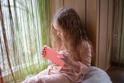 Young woman using mobile phone while sitting on sofa at home