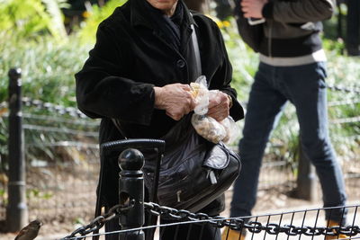 Midsection of woman standing with food packets at park