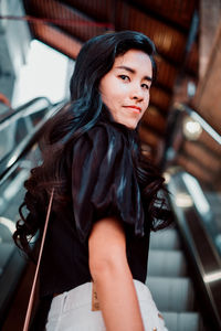 Portrait of young woman standing on escalator