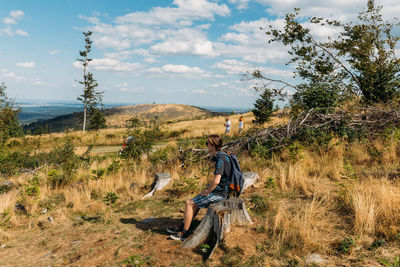 Side view of man with backpack sitting on land