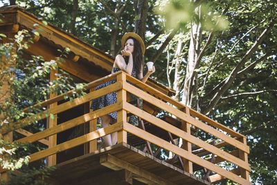 Young woman standing on the tree house balcony