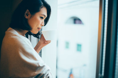 Young woman looking through window