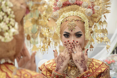 Reflection of beautiful bride in mirror covering her mouth with hands