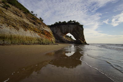 Rock formations on sea shore against sky