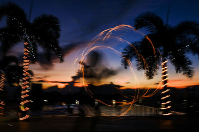 Blurred motion of silhouette palm trees against sky at night