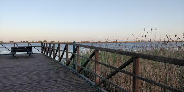 Pier over sea against clear sky during sunset