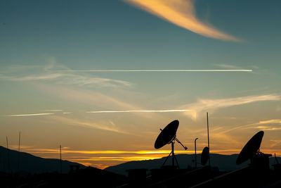 Silhouette of communications tower against sky during sunset