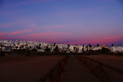 Footpath amidst buildings in city at sunset