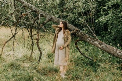 Woman standing by tree in forest