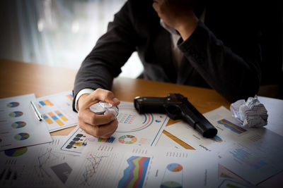 Midsection of man holding paper while sitting on table