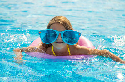 Girl wearing novelty glasses swimming in pool