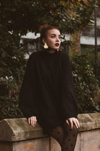 Portrait of young woman standing against plants