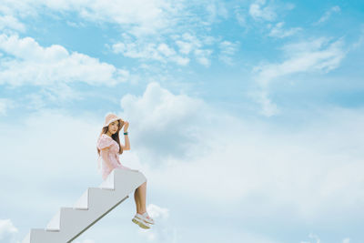 Low angle view of woman standing against sky