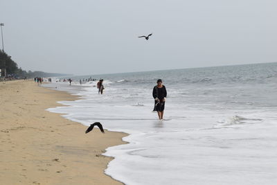 People at beach against clear sky
