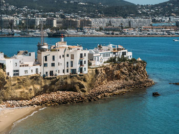 View from the sea to old white houses on the rock on a sunny day. port of ibiza, spain.