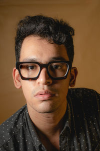 A man with big brown acetate eyeglasses and grey polka dot shirt.