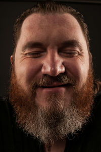 Close-up of bearded man over black background
