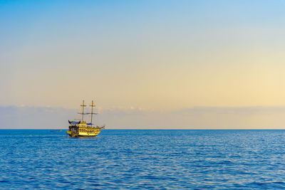 Ship sailing in sea against sky during sunset