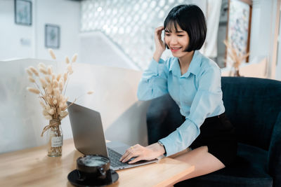 Young businesswoman using mobile phone while sitting on sofa at home