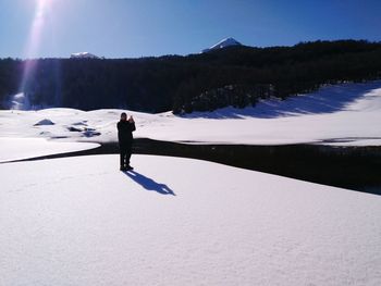 Man walking on snow covered mountain against sky