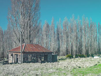 House amidst trees on field against sky