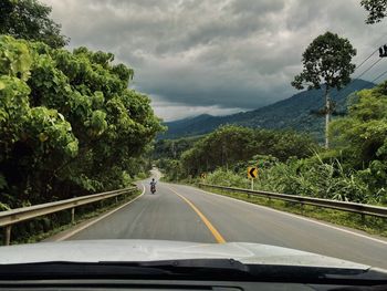 Empty road amidst trees against sky