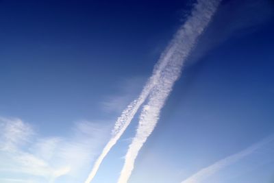 Low angle view of vapor trail against blue sky