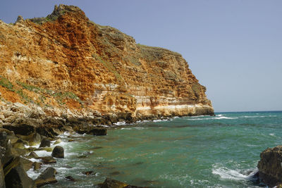 Scenic view of rocks in sea against clear sky