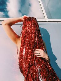 Young woman covered with red decoration by wall