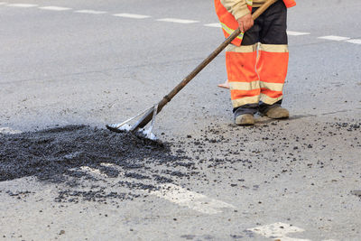 Low section of man working on road at construction site