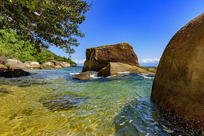 Rocks on beach against clear blue sky