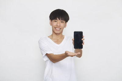 Portrait of smiling man photographing against white background