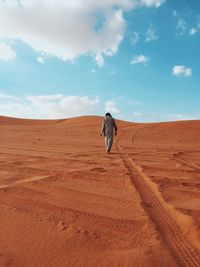 Rear view of man walking on desert