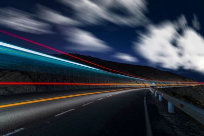 Light trails on road against sky