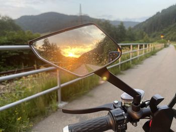Close-up of bicycle wheel by road against sky during sunset
