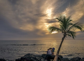 People on beach against sky during sunset