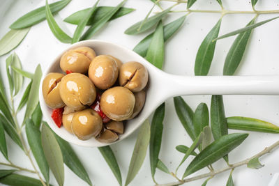 Spiced olives on white spoon and wood background. spanish tapa