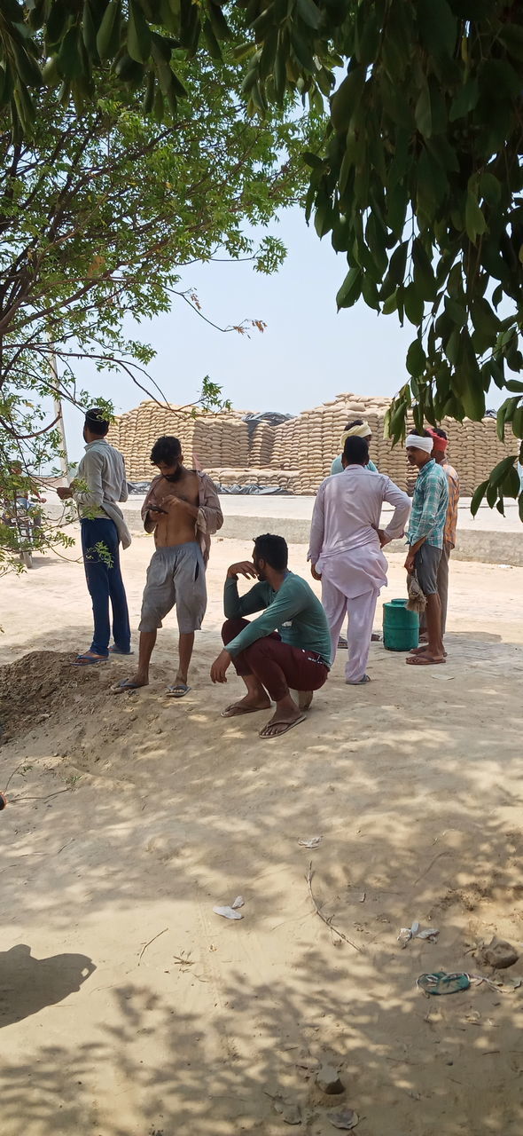 REAR VIEW OF PEOPLE ENJOYING ON SAND AT PARK