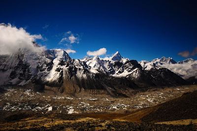 Scenic view of snowcapped mountains against blue sky